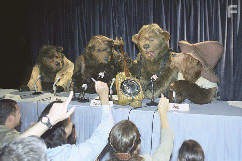 Influential rock group The Country Bears (left to right: Ted Bedderhead, Fred Bedderhead, Tennessee O'Neal, and Zeb Zoober) show off Tennessee's "One-String Thang" to reporters as they prepare for their reunion concert.