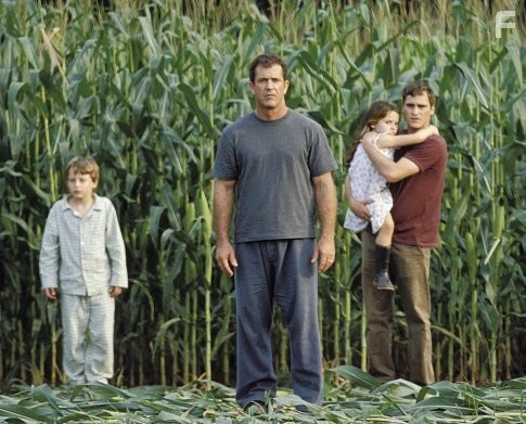 Graham Hess (Mel Gibson, center left), along with his son, Morgan (Rory Culkin, left), his daughter, Bo (Abigail Breslin, center right), and his brother, Merrill (Joaquin Phoenix, right), investigate the strange occurrence.
