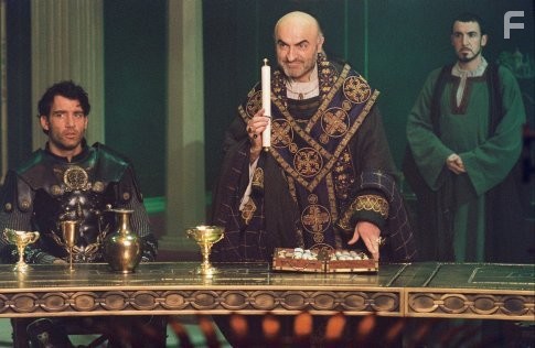 Arthur (Clive Owen, left) listens as Bishop Germanius (Ivano Marescotti, center) requests a final challenge of Arthur's Knights of the Round Table while Horton (Pat Kinevane, right) looks on.